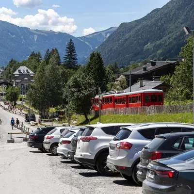 a row of cars parked in a parking lot with a red train at Appartement Le Galetas des Planards in Chamonix-Mont-Blanc