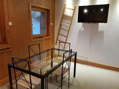 a room with a glass table and a tv and a shelf at Appartement Le Caboen Les Planards in Chamonix-Mont-Blanc