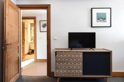a living room with a tv on top of a cabinet at Appartement Le Caboen Les Planards in Chamonix-Mont-Blanc