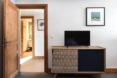 a living room with a flat screen tv on a cabinet at Appartement Le Caboen Les Planards in Chamonix-Mont-Blanc
