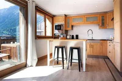 a kitchen with a counter and two bar stools at Appartement Le Mazot Vue Mont Blanc in Chamonix-Mont-Blanc