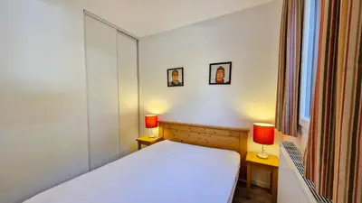 a bedroom with a white bed and two lamps at Residence les Pleiades in Flaine