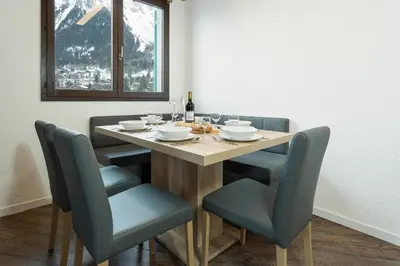 a dining room table with chairs and a bottle of wine at Apartment Balme 5 - Chamonix Mont Blanc in Chamonix-Mont-Blanc