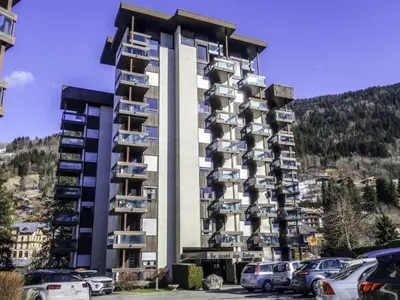a large building with cars parked in a parking lot at Castel des roches Leal Julien in Saint-Gervais-les-Bains