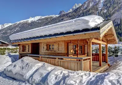 a log cabin in the snow with a mountain at Chalets Ile des Barrats in Chamonix-Mont-Blanc