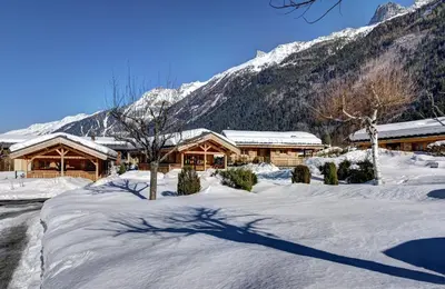 a lodge in the snow with mountains in the background at Chalets Ile des Barrats in Chamonix-Mont-Blanc