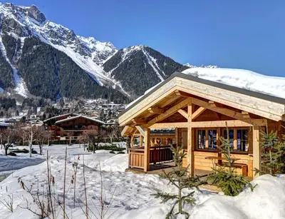 a cabin in the snow with mountains in the background at Chalets Ile des Barrats in Chamonix-Mont-Blanc