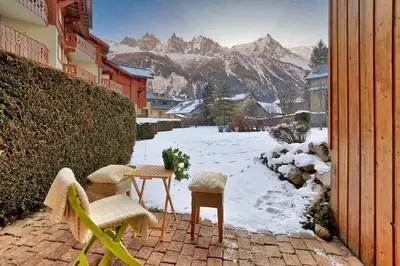 a patio with two chairs and a table in the snow at Petite Jardin: Residence Via des Traz B in Chamonix-Mont-Blanc