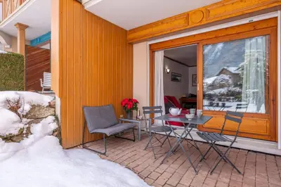 a patio with a table and chairs in the snow at Petite Jardin: Residence Via des Traz B in Chamonix-Mont-Blanc