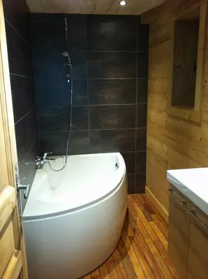 a bathroom with a white tub and wooden floors at Chalet Narcisse in Sixt