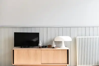a television on a cabinet with a lamp on it at Appartement La Vallée Blanche avec parking gratuit in Chamonix-Mont-Blanc