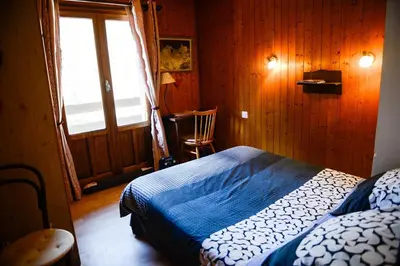 a bedroom with a bed and a window and a chair at Crêmerie Balmat in Chamonix-Mont-Blanc