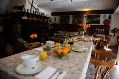 a table with plates and bowls of oranges and a fireplace at Crêmerie Balmat in Chamonix-Mont-Blanc