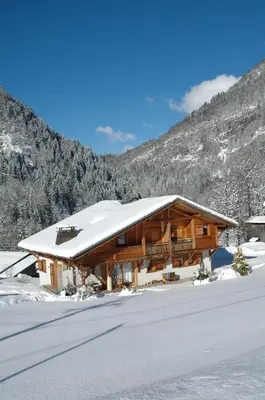 a log cabin in the snow with mountains in the background at Chalet La R'Batte in Sixt