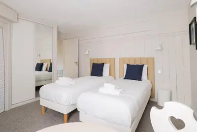 two beds in a white room with blue pillows at Hôtel des 2 Gares in Saint-Gervais-les-Bains