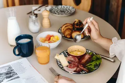 a table with plates of food and a person with a spoon at Hôtel des 2 Gares in Saint-Gervais-les-Bains