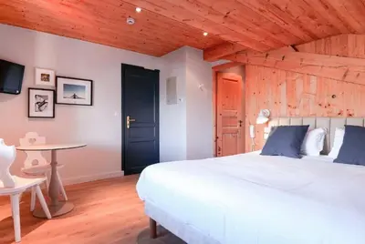a bedroom with a large white bed and a table at Hôtel des 2 Gares in Saint-Gervais-les-Bains