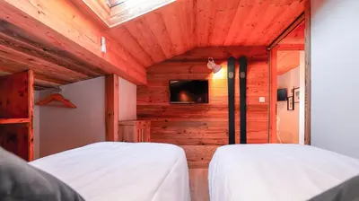 two beds in a room with wooden walls at Hôtel des 2 Gares in Saint-Gervais-les-Bains