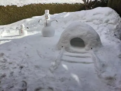 a snow house with two snowmen sitting in the snow at le Montagny in Les Houches