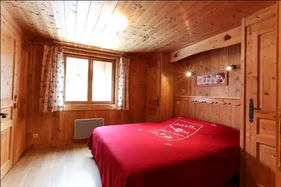 a bedroom with a red bed in a wooden room at le Montagny in Les Houches