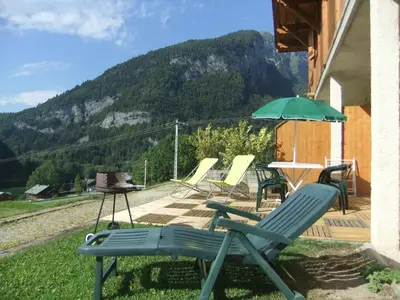 a group of chairs and an umbrella on a patio at Chalet des Cascades in Sixt