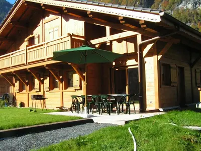 a wooden house with a table and chairs and an umbrella at Chalet des Cascades in Sixt