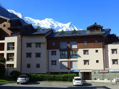 a building with two cars parked in a parking lot with a mountain at Apartment L'Espace Montagne-5 by Interhome in Chamonix-Mont-Blanc