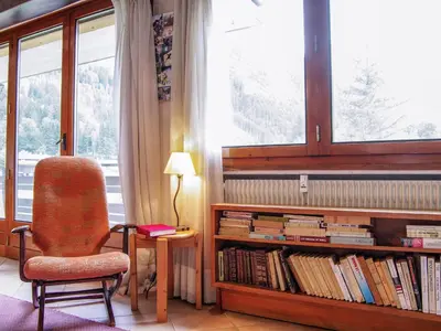 a room with a chair and a book shelf with books at Apartment Le Bois du Bouchet-1 by Interhome in Chamonix-Mont-Blanc