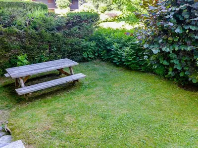 a wooden bench sitting in the grass in a yard at Apartment Champraz-7 by Interhome in Chamonix-Mont-Blanc