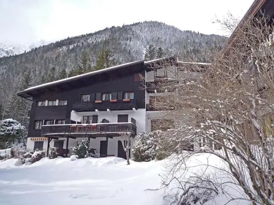 a large building in the snow in front of a mountain at Apartment Les Charmoz-3 by Interhome in Chamonix-Mont-Blanc