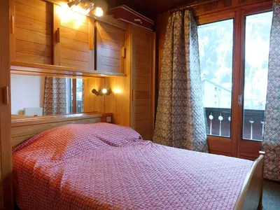 a bedroom with a bed with a red comforter and a window at Apartment Les Charmoz-3 by Interhome in Chamonix-Mont-Blanc