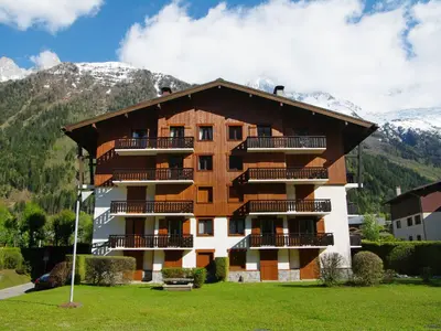 a building with snowy mountains in the background at Apartment Le Choucas by Interhome in Chamonix-Mont-Blanc