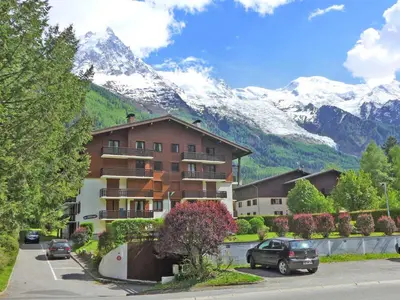 a large apartment building with mountains in the background at Apartment Le Choucas by Interhome in Chamonix-Mont-Blanc