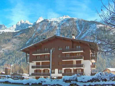 a building with balconies and snow covered mountains at Apartment Le Choucas by Interhome in Chamonix-Mont-Blanc