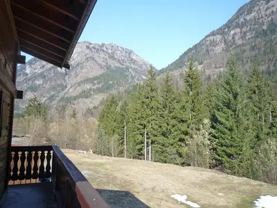 a large wooden cabin with a porch in the grass at Chalet Pierre Blanche by Interhome in Servoz