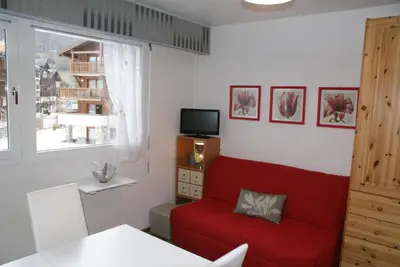 a living room with a red couch and a television at Multi résidences Samoëns in Samoëns