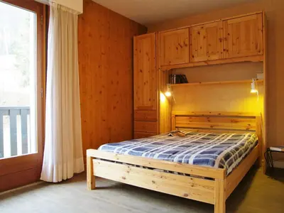 a bedroom with a wooden bed and a window at Apartment Les Aiguilles du Brévent by Interhome in Chamonix-Mont-Blanc