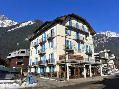 a large building with blue windows and mountains in the background at Apartment Le Savoisien by Interhome in Chamonix-Mont-Blanc