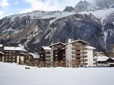 a building in the snow in front of a mountain at Apartment Clos du Savoy-15 by Interhome in Chamonix-Mont-Blanc