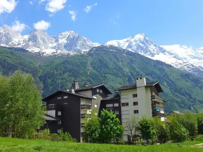 a building with snow capped mountains in the background at Apartment Clos du Savoy-15 by Interhome in Chamonix-Mont-Blanc