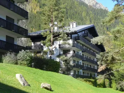 a building on a hill next to a grassy field at Apartment Le Brévent-14 by Interhome in Chamonix-Mont-Blanc
