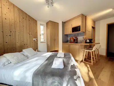 a bedroom with a large bed and a kitchen at Le Caribou in Chamonix-Mont-Blanc