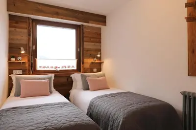two beds in a room with a window at Le Brevent 1 Apartment in Chamonix-Mont-Blanc