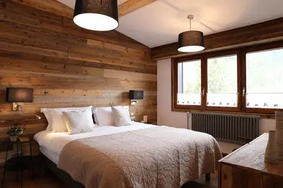 a bedroom with a bed with wooden walls and windows at Le Brevent 1 Apartment in Chamonix-Mont-Blanc