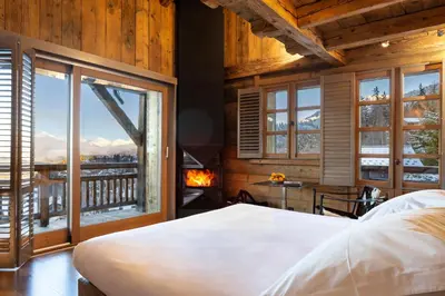 a bedroom with a bed and a fireplace and a window at Hôtel Les Servages d'Armelle in Les Carroz d'Araches