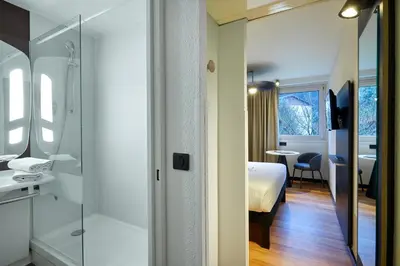 a bedroom with a bed and a table and a chair at Ibis Sallanches Porte du MontBlanc in Sallanches