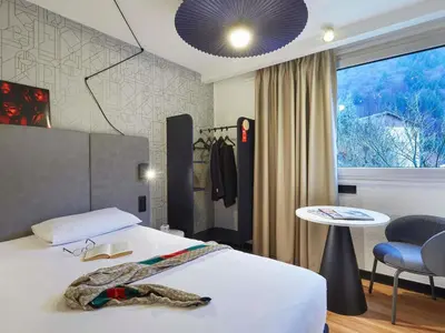 a bedroom with a bed and a table and a chair at Ibis Sallanches Porte du MontBlanc in Sallanches
