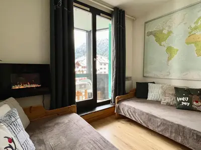 a living room with a window and a couch and a map at Le Balme Studio WiFi/Parking/Balcony in Chamonix-Mont-Blanc