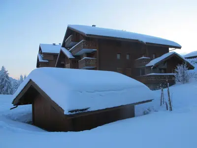 a building covered in snow with a pile of snow at Chalet Les Trappeurs in Les Carroz d'Araches