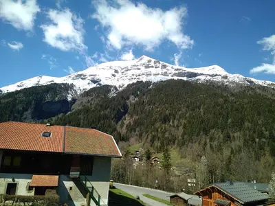 a snow covered mountain in front of a house at Le Nant in Les Contamines-Montjoie